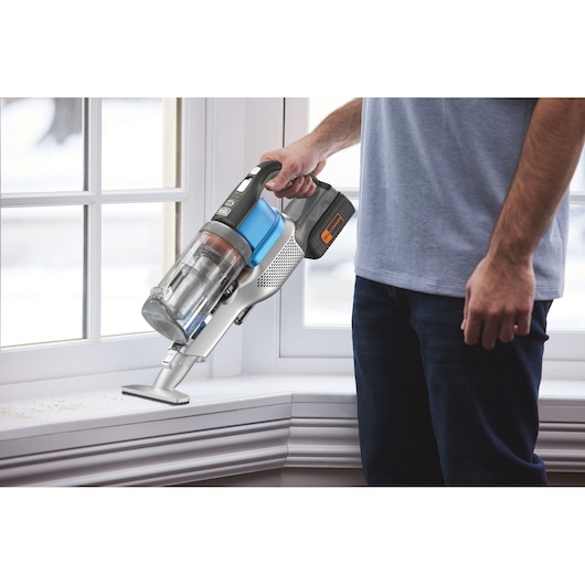 BLACKDECKER BHFEV362D cordless handheld vacuum in use cleaning a white windowsill.