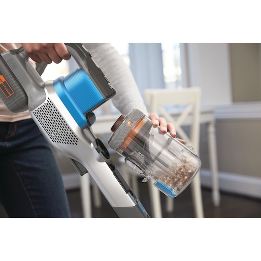 BLACKDECKER BHFEV362D cordless vacuum cleaner with blue and grey body, dustbin being emptied indoors.