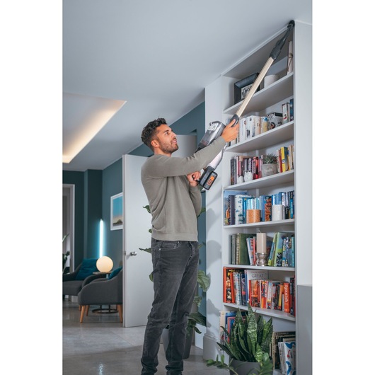 BLACKDECKER BHFEV36B2D cordless vacuum cleaning bookshelf corner in modern living room.