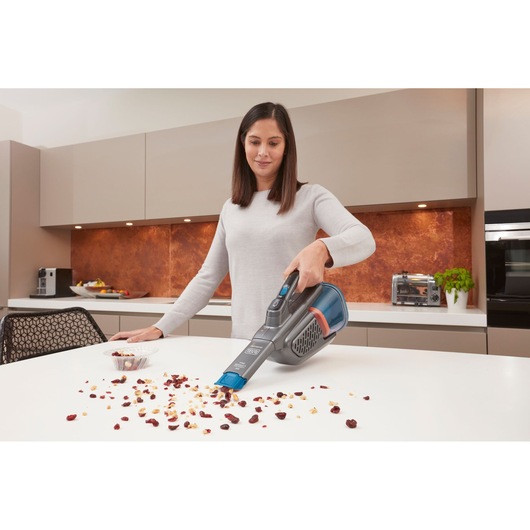 BLACKDECKER BHHV320J handheld vacuum cleaner being used to clean crumbs from a kitchen countertop.