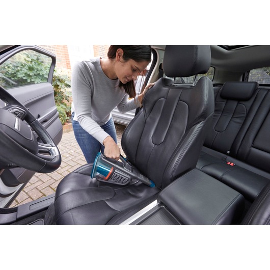 BLACKDECKER BHHV320J handheld vacuum cleaning black car seat upholstery.