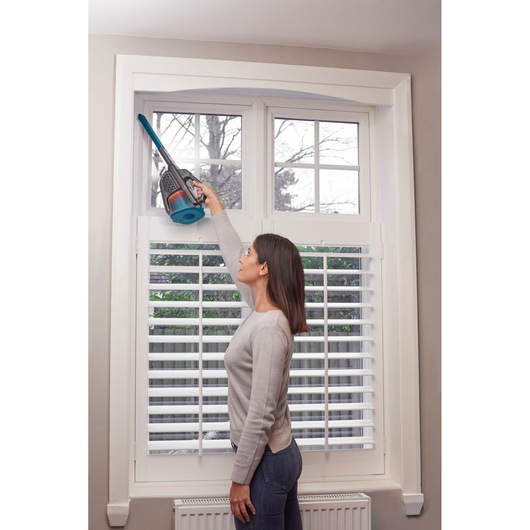 BLACKDECKER BHHV320J handheld vacuum used for cleaning window frame indoors.