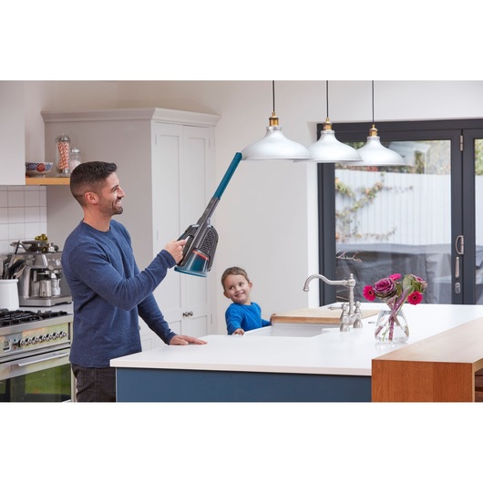 BLACKDECKER BHHV320J handheld vacuum with extension cleaning a pendant light in a modern kitchen.