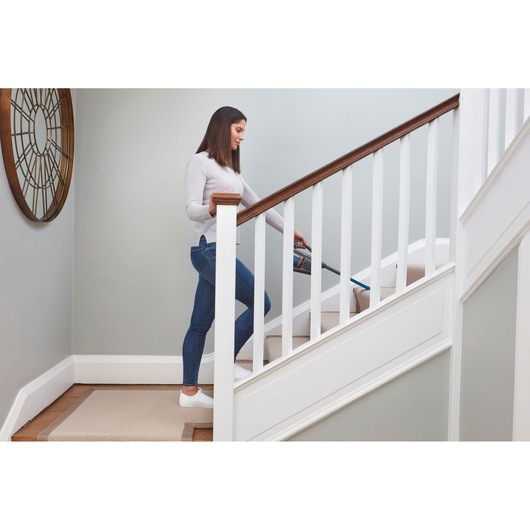 BLACKDECKER BHHV320J handheld vacuum used on carpeted stairs in a home interior.
