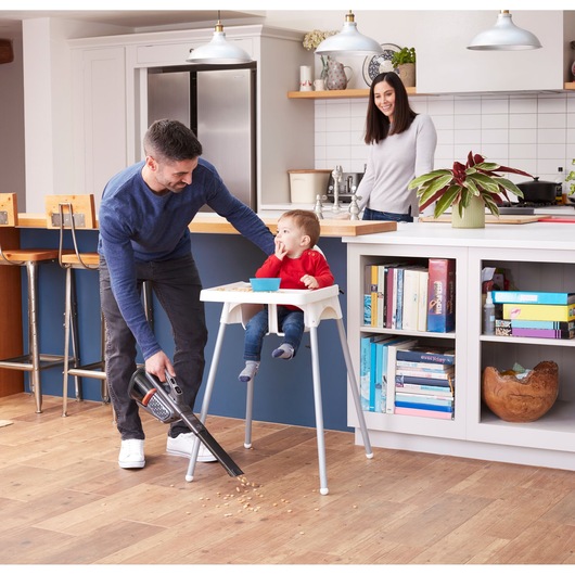 BLACKDECKER BHHV520JF handheld vacuum cleaning food debris by high chair in modern kitchen.