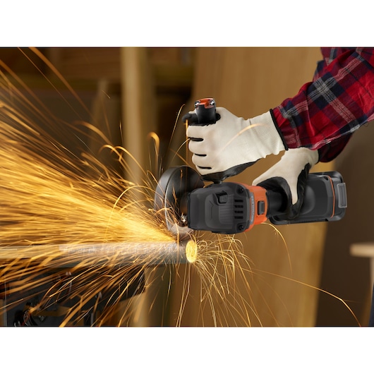 BLACKDECKER BLCG78M1 angle grinder in use cutting metal pipe with bright sparks, gloved hands holding tool.