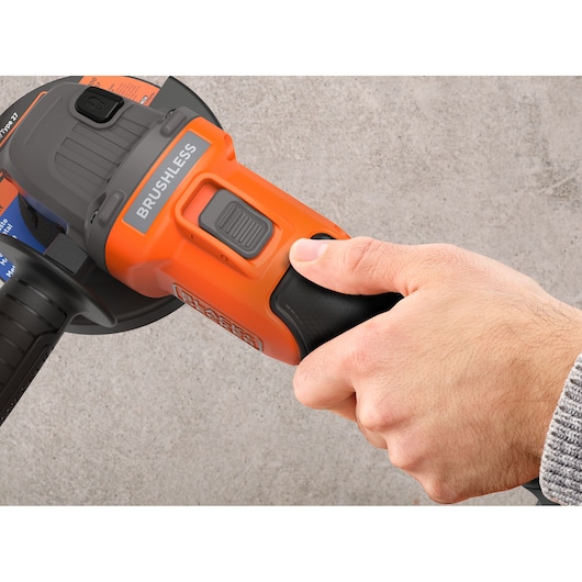 Photo of BLACKDECKER BLCG78M1 brushless angle grinder handle being gripped by a hand, close-up detail.
