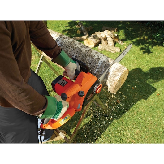 Photo of BLACKDECKER CS2040 chainsaw cutting a log outdoors, orange and black tool held by gloved hands.
