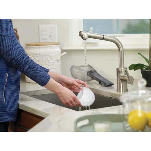 Photo of BLACKDECKER DVA315J handheld vacuum filter being rinsed under a kitchen faucet.