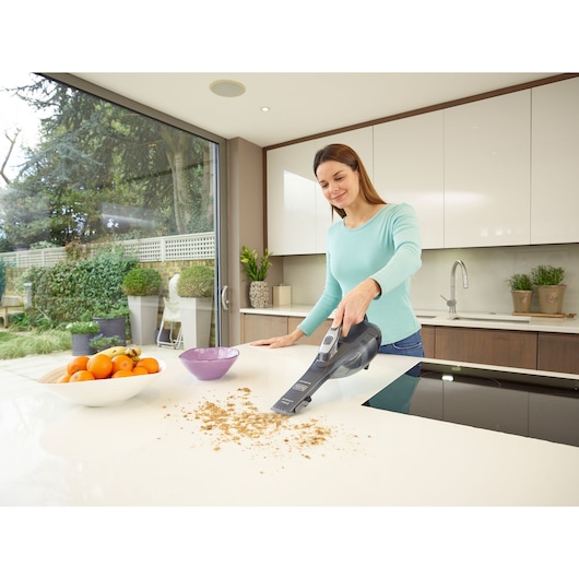 BLACKDECKER DVA320J handheld vacuum cleaning crumbs on a modern kitchen counter.