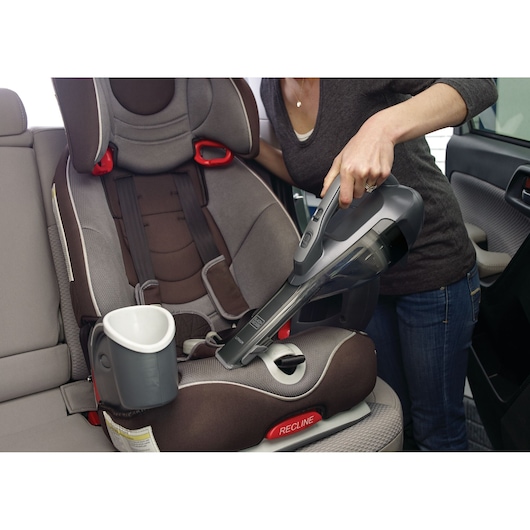 BLACKDECKER DVA320J handheld vacuum cleaning a child's car seat inside a vehicle.