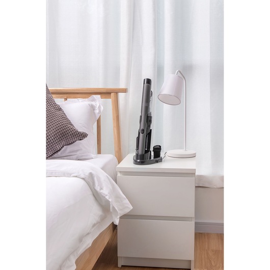 BLACKDECKER DVC320B21 cordless handheld vacuum on white nightstand next to modern lamp in bedroom.
