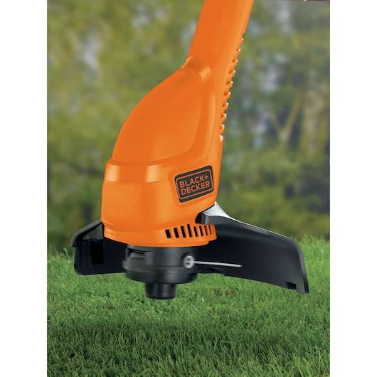 Close-up of BLACK+DECKER GL310 orange grass trimmer head on lawn outdoors.