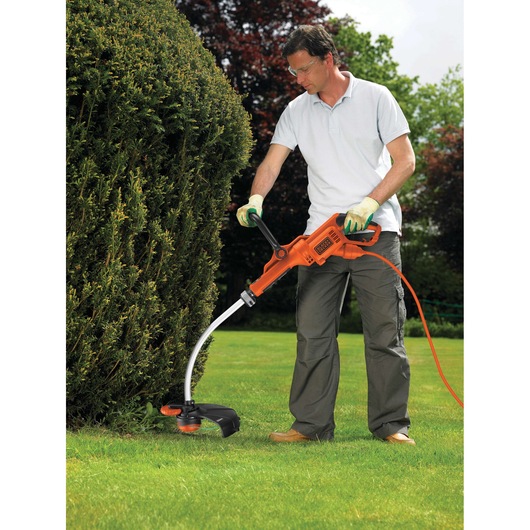 BLACKDECKER GL9035 grass trimmer used outdoors with orange cord, held by person wearing gloves.