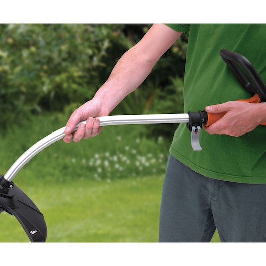 BLACK+DECKER GL9035 grass trimmer handle close-up showing ergonomic grip in use outdoors.