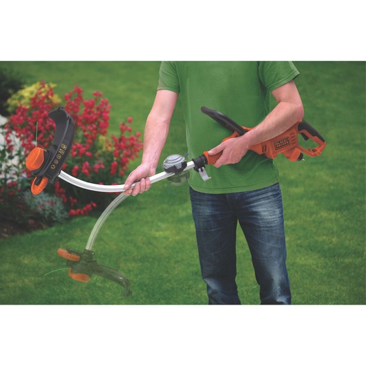 BLACKDECKER GL9035 grass trimmer held by person on lawn, orange and black design, adjustable shaft.