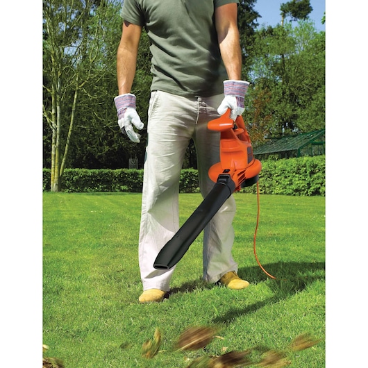 BLACKDECKER GW3030 electric leaf blower in use on grass, person wearing gloves and holding the orange tool.