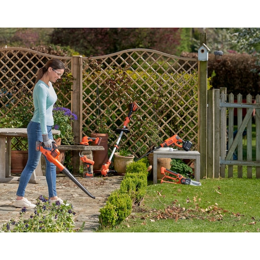 Photo of BLACKDECKER GWC1820PC leaf blower in use on garden path, with other garden tools visible in background.