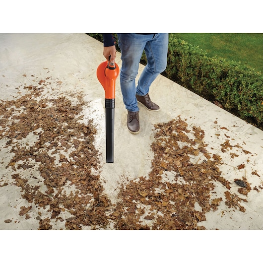 BLACKDECKER GWC1820PC leaf blower used on patio with scattered dry leaves, held by person in blue jeans.