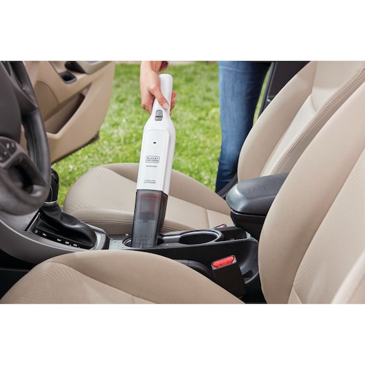Photo of BLACKDECKER HLVC315B11 cordless handheld vacuum cleaning a car’s interior between front seats.