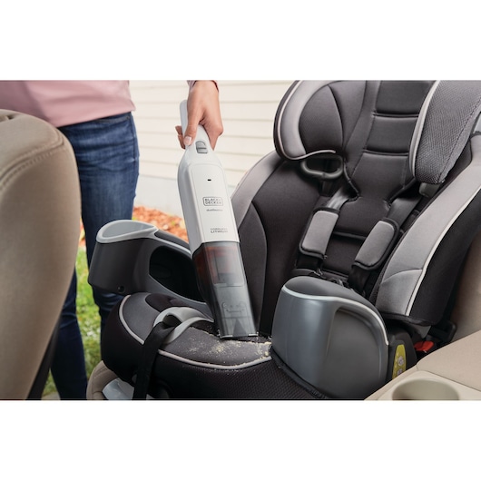 BLACKDECKER HLVC315B11 handheld vacuum cleaning crumbs from a black and gray car seat.