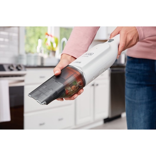 BLACKDECKER HLVC315B11 handheld vacuum in use cleaning crumbs in a kitchen.
