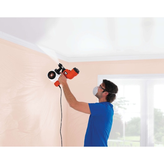 Person using BLACKDECKER HVLP200 paint sprayer on interior ceiling near a window.