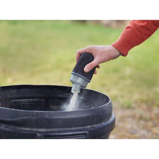 BLACKDECKER KA199 dust filter being tapped over a black container outdoors.
