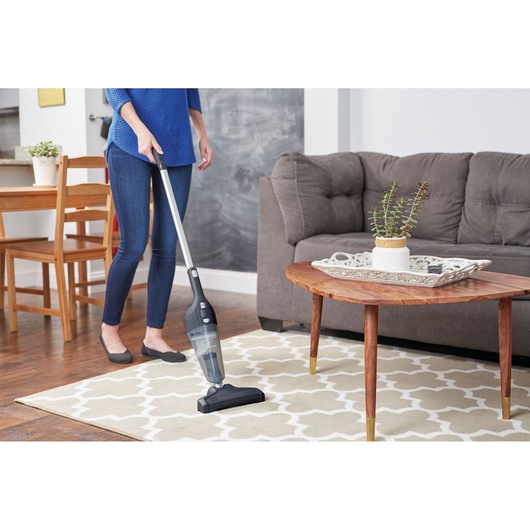 BLACKDECKER NSVA315J stick vacuum cleaner in use on patterned rug in living room setting.