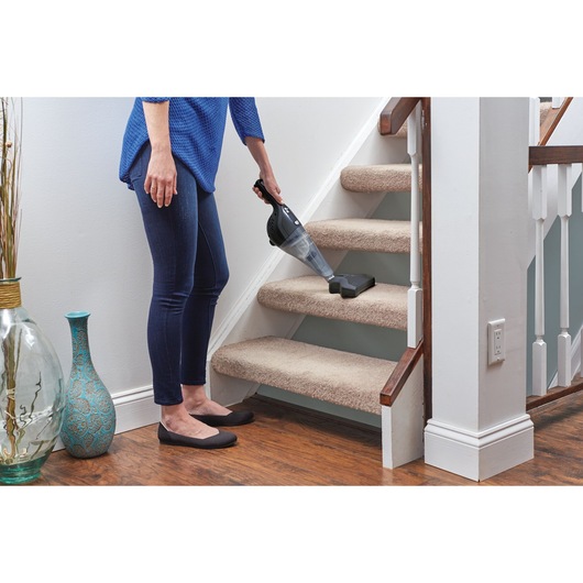 BLACKDECKER NSVA315J handheld vacuum cleaning carpeted stairs in home setting.