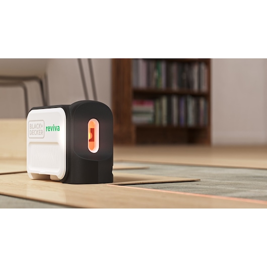 BLACKDECKER REVBDLL100 laser level on floor with orange beam, home interior background.