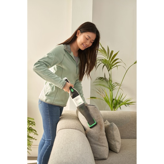 BLACKDECKER REVHV8C handheld vacuum cleaning sofa cushions in living room setting