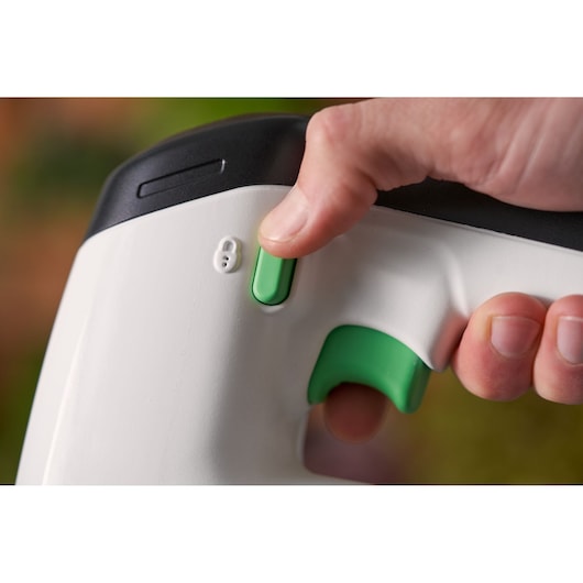 Close-up photo of BLACKDECKER REVJ12C tool handle, white with green buttons and trigger operated by hand.
