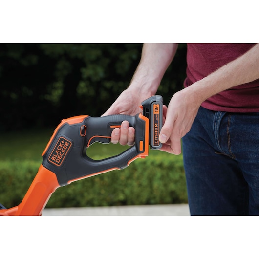 BLACKDECKER STC1820EPC cordless tool handle with person inserting 18V lithium battery outdoors.