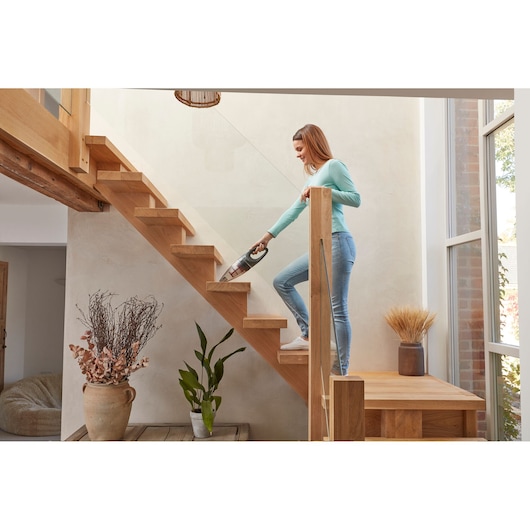 BLACKDECKER SVB520JW handheld vacuum used on wooden stairs in a modern home setting.