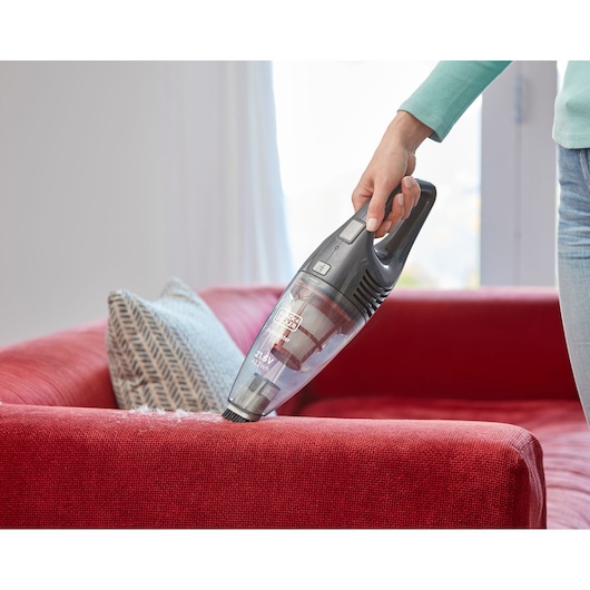BLACK+DECKER SVB620JW handheld vacuum cleaning red fabric sofa with person holding it.