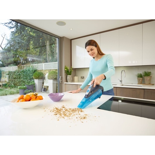 BLACK+DECKER WDA320J handheld vacuum cleaner used on a kitchen counter to clean crumbs.