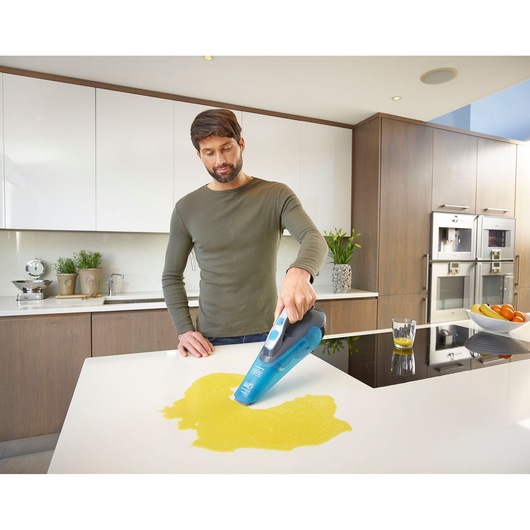 BLACK+DECKER WDA320J handheld vacuum cleaner cleaning liquid spill on kitchen counter.
