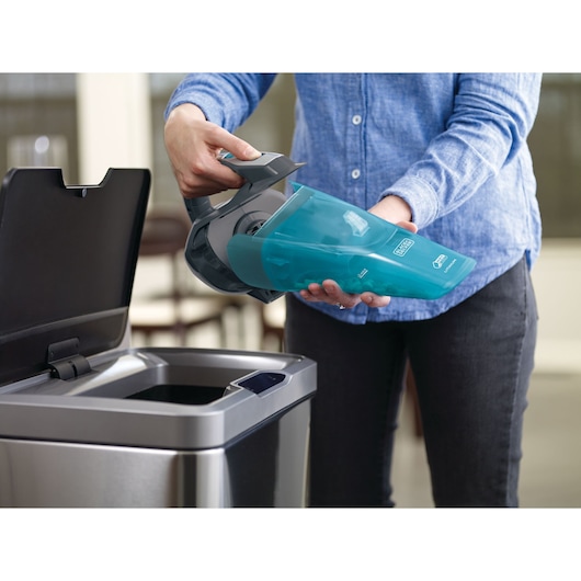 Photo of BLACKDECKER WDA320J handheld vacuum being emptied into a stainless steel trash bin.
